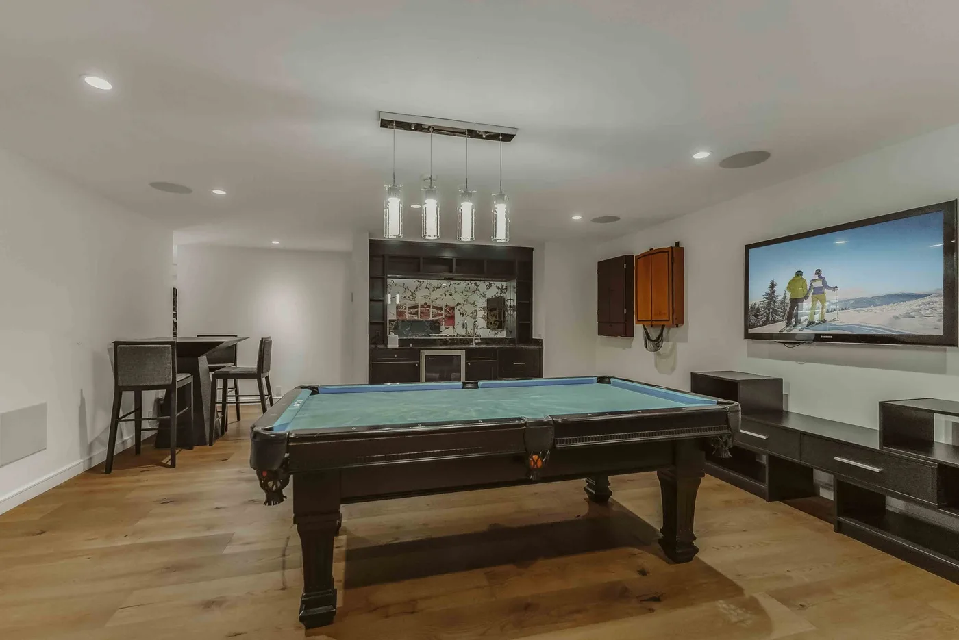 A game room features a pool table, with a bar area behind it.