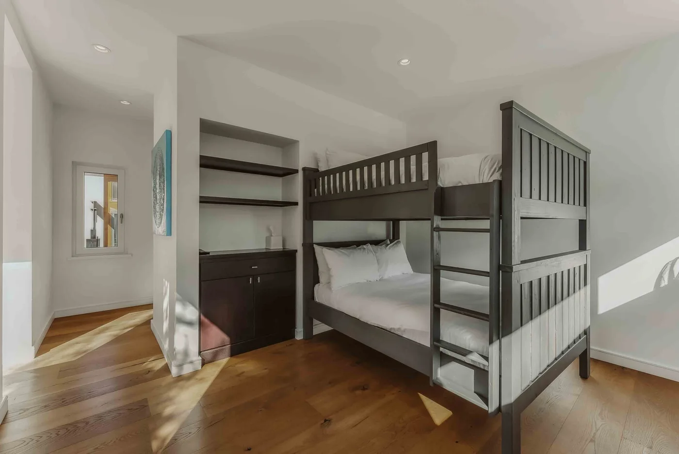 A bedroom with a dark bunk bed and built-in shelving.