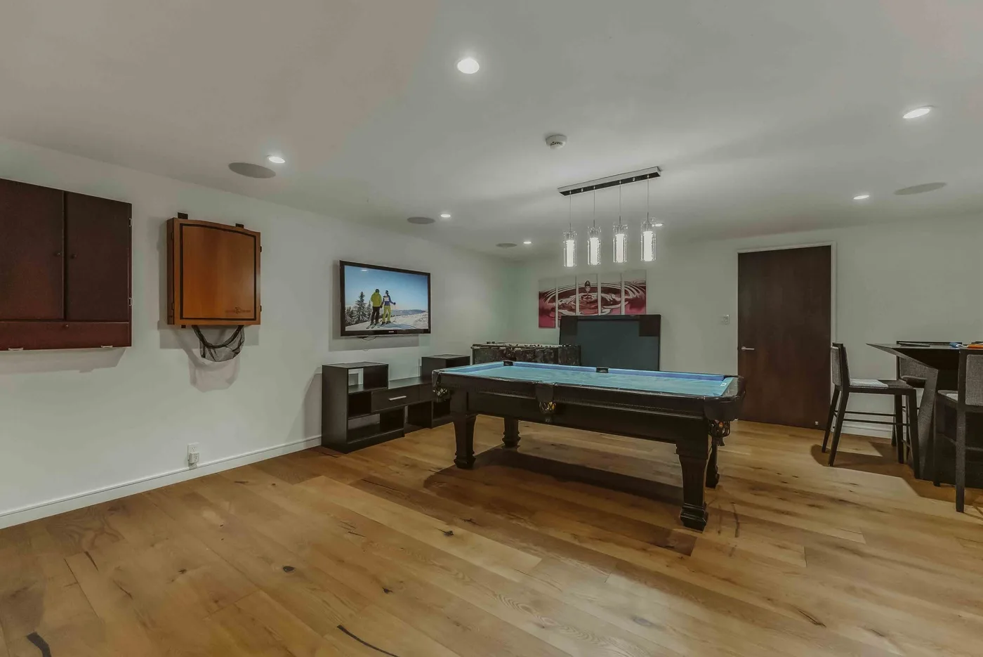 A recreation room with a pool table, wall-mounted television, and seating.