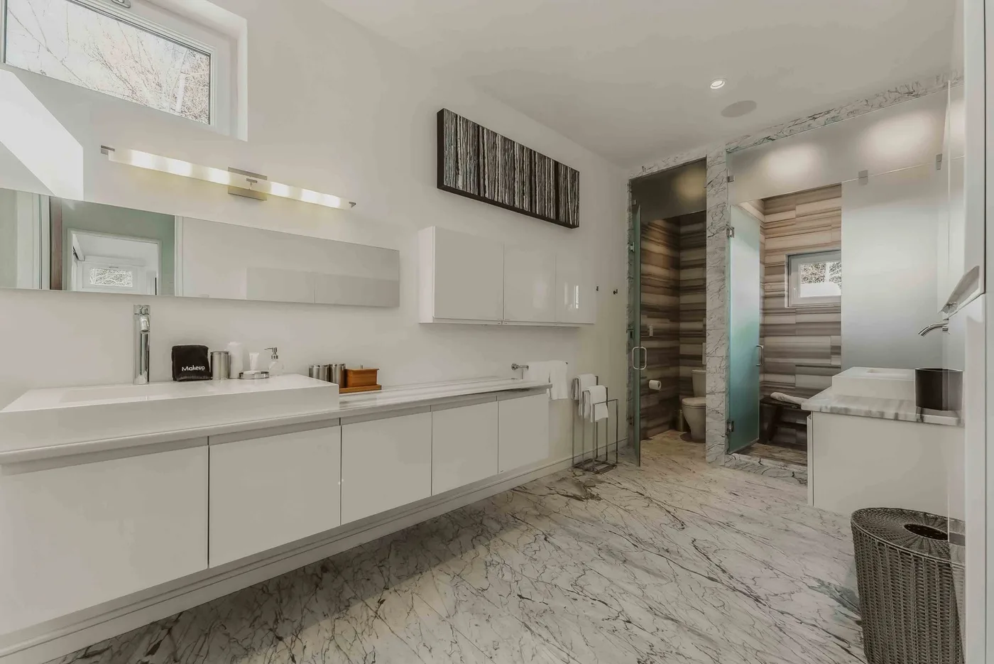 A bright bathroom with a long vanity, wall mirror, and walk-in shower.