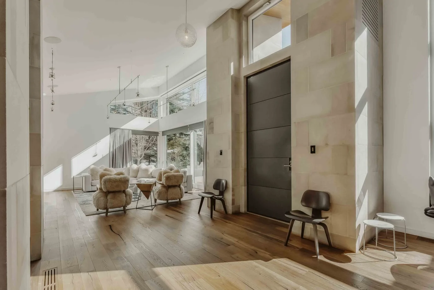 A bright living room with seating beside a tall dark entry door.