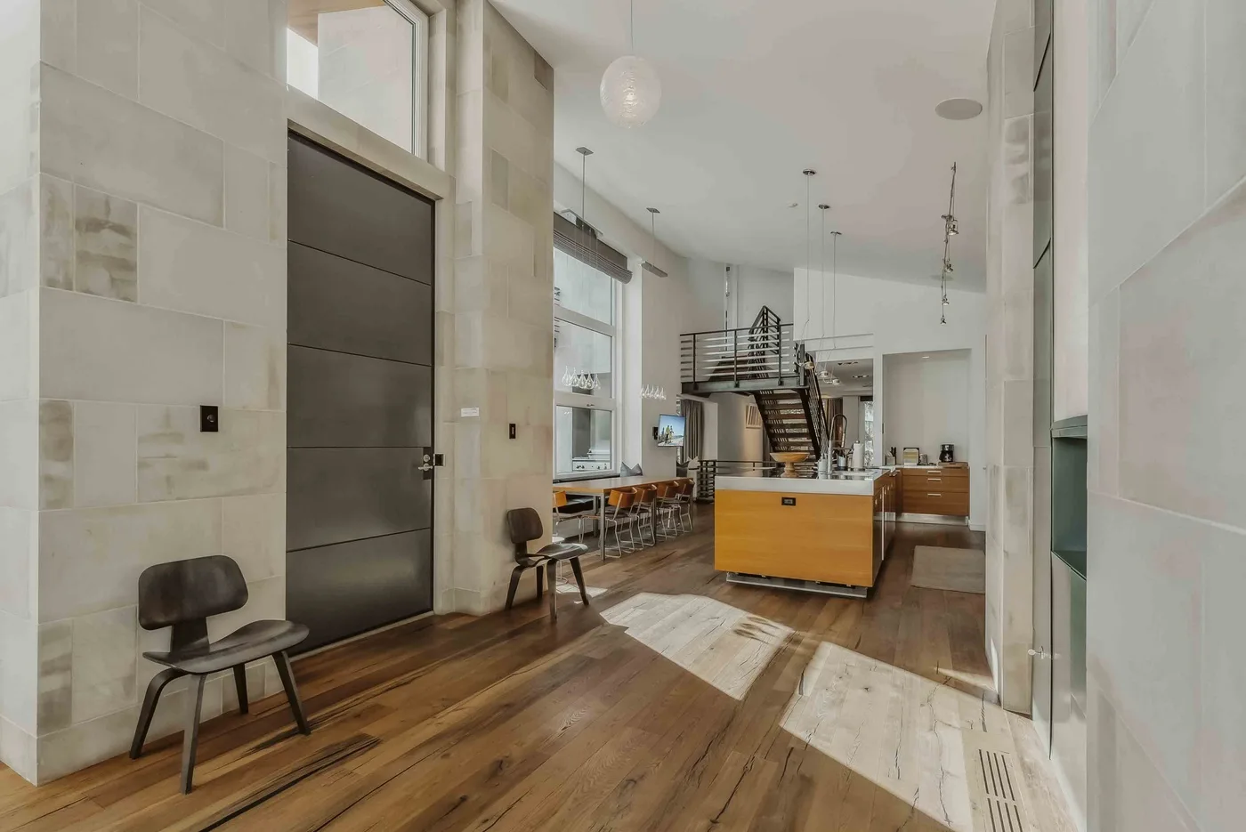 A bright open interior with a wood floor, dining table, and staircase.