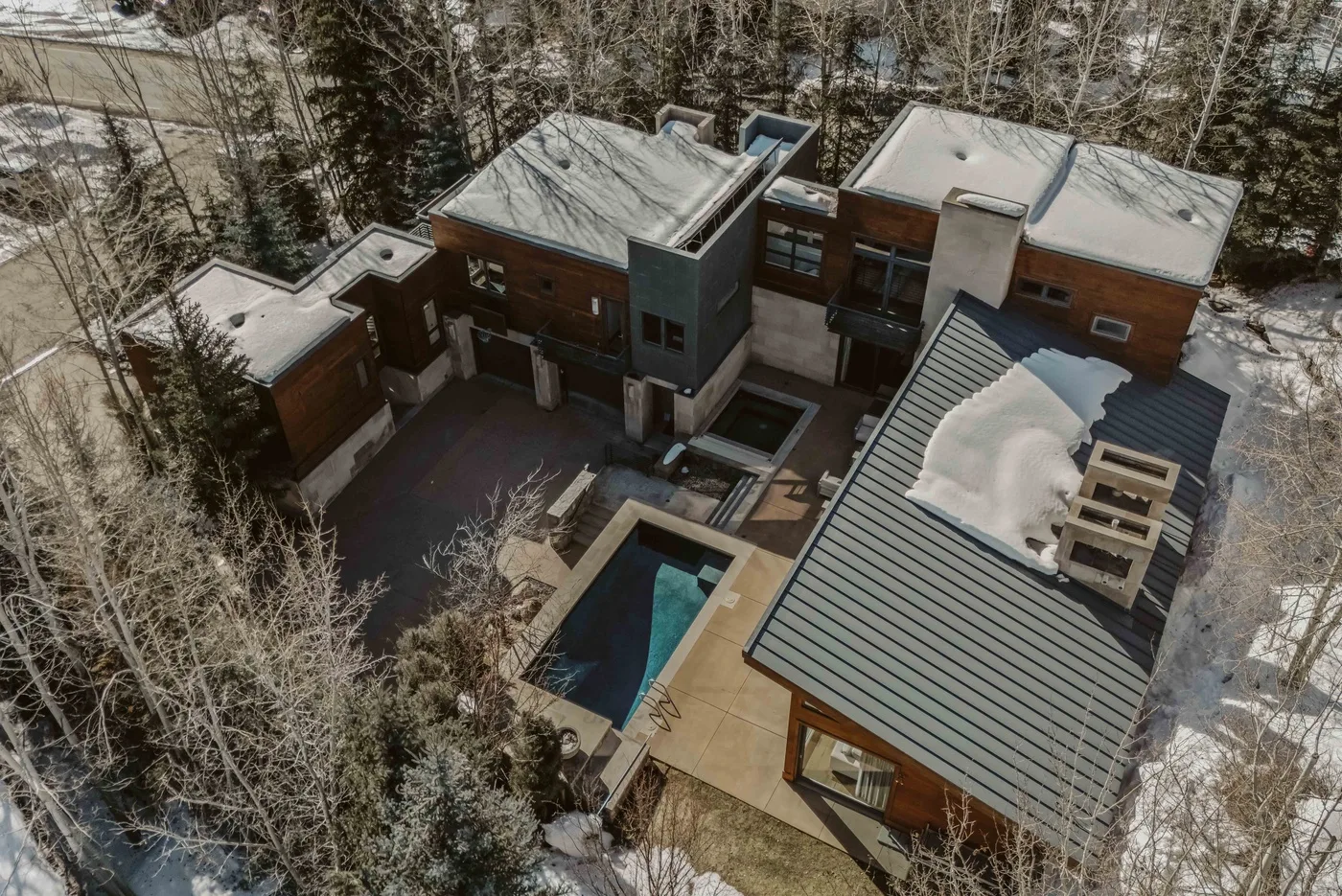 An aerial view of a modern house with a pool and snow-covered roofs.