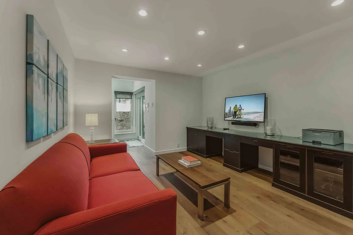 A living room with red seating, a coffee table, and a television.