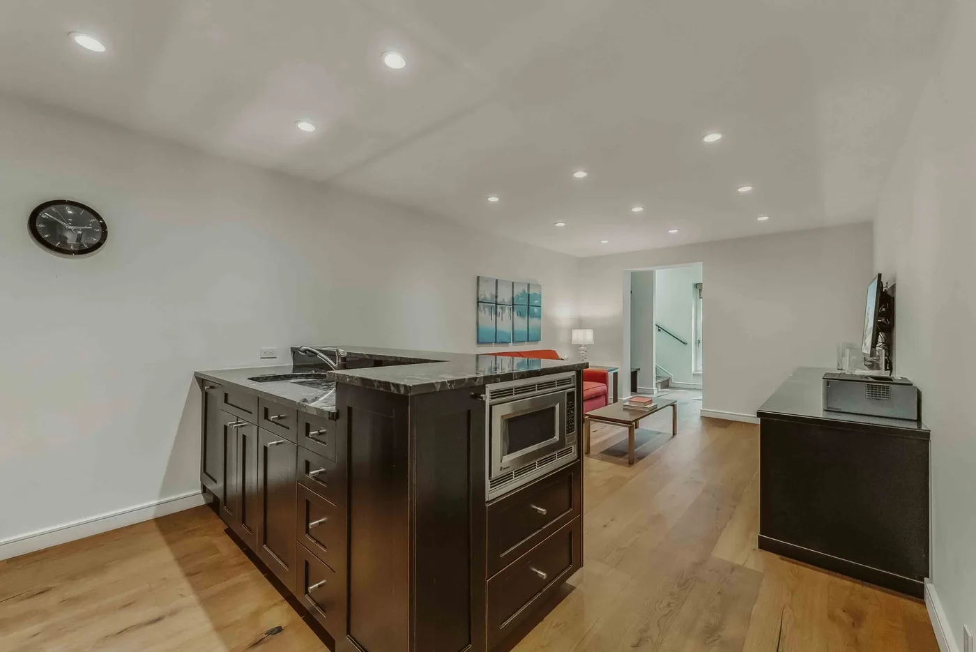 A modern kitchen with dark cabinetry, a central island, and light wood flooring.