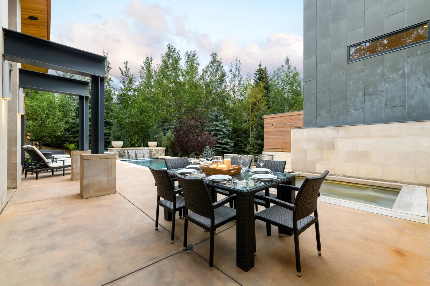 An outdoor dining area with a table and seating beside a swimming pool.