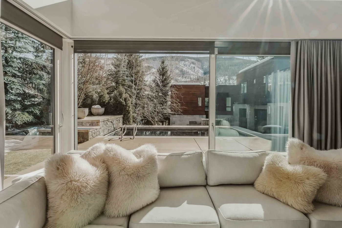 A bright living room with cushioned seating and large windows overlooking a snowy landscape.