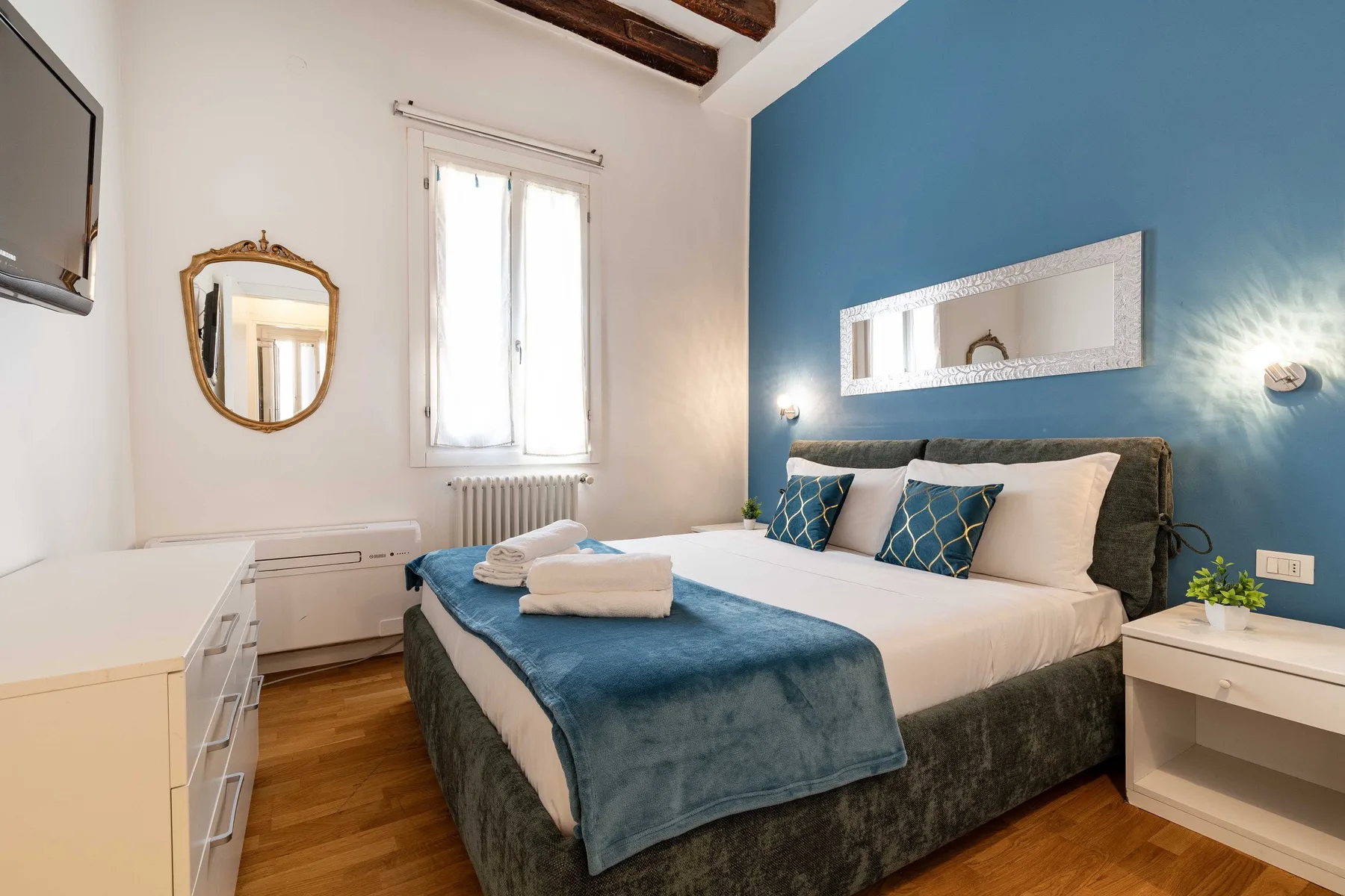 A bedroom with a bed dressed in blue and white bedding.