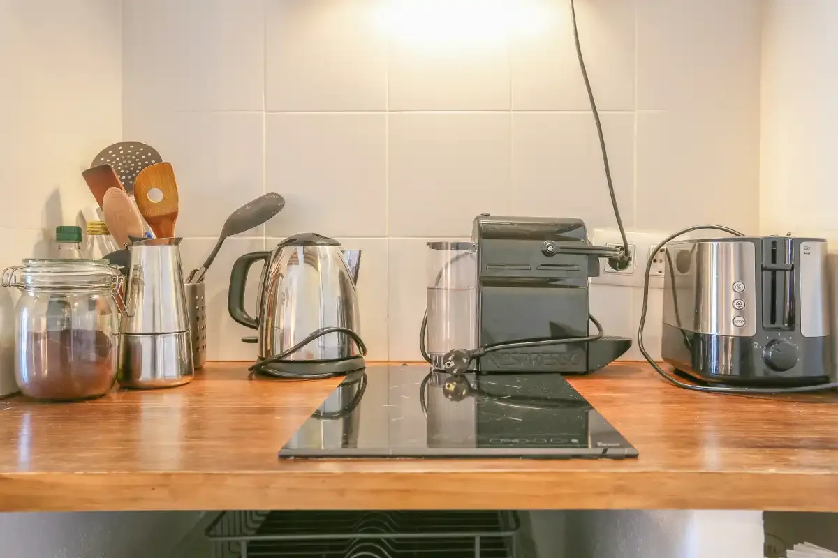 A kitchen counter with a cooktop, kettle, and small appliances.