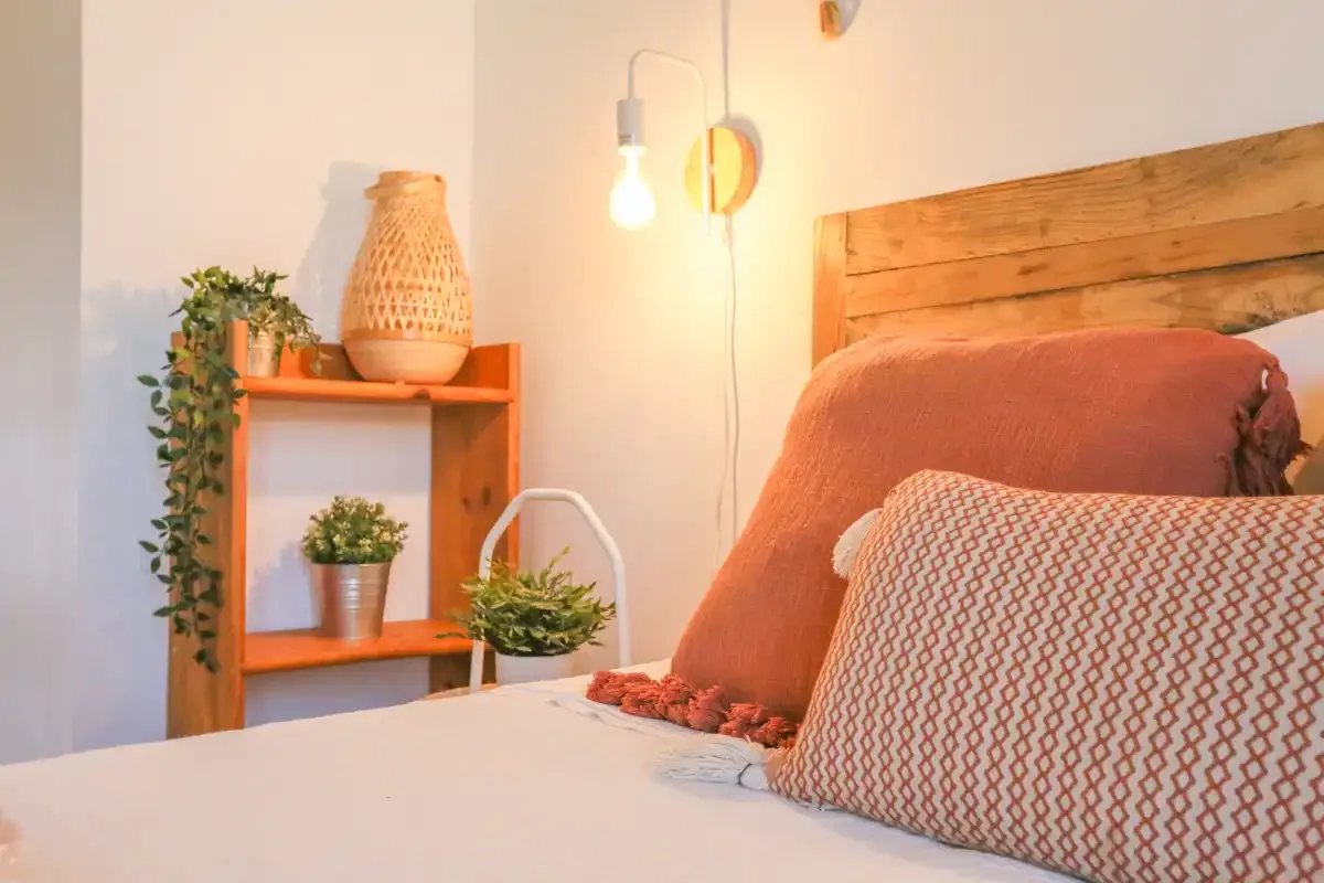 A bedroom with a bed, patterned pillows, and a wooden headboard.