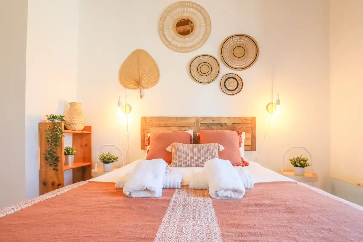 A bedroom with a neatly made bed and woven wall decorations.