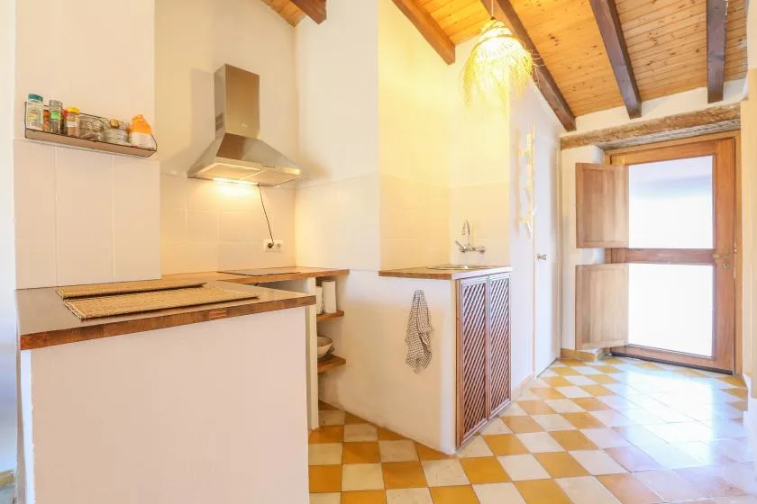A bright kitchen with a cooktop, range hood, and checkered tile floor.