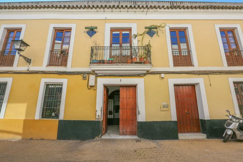 A yellow building facade with wooden doors, windows, and a small balcony.