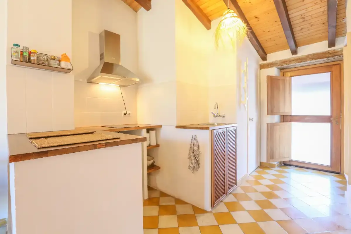 A bright kitchen with a tiled floor and a wooden ceiling.