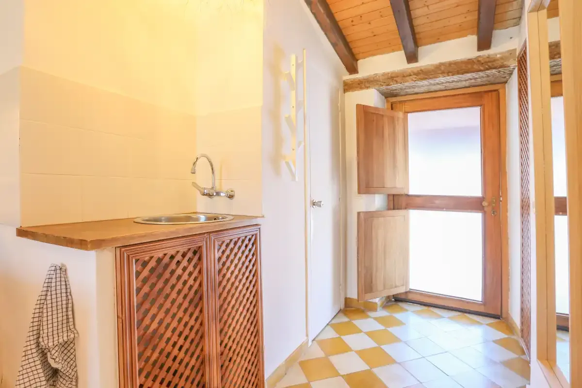 A tiled interior entryway with a wooden door and washbasin.