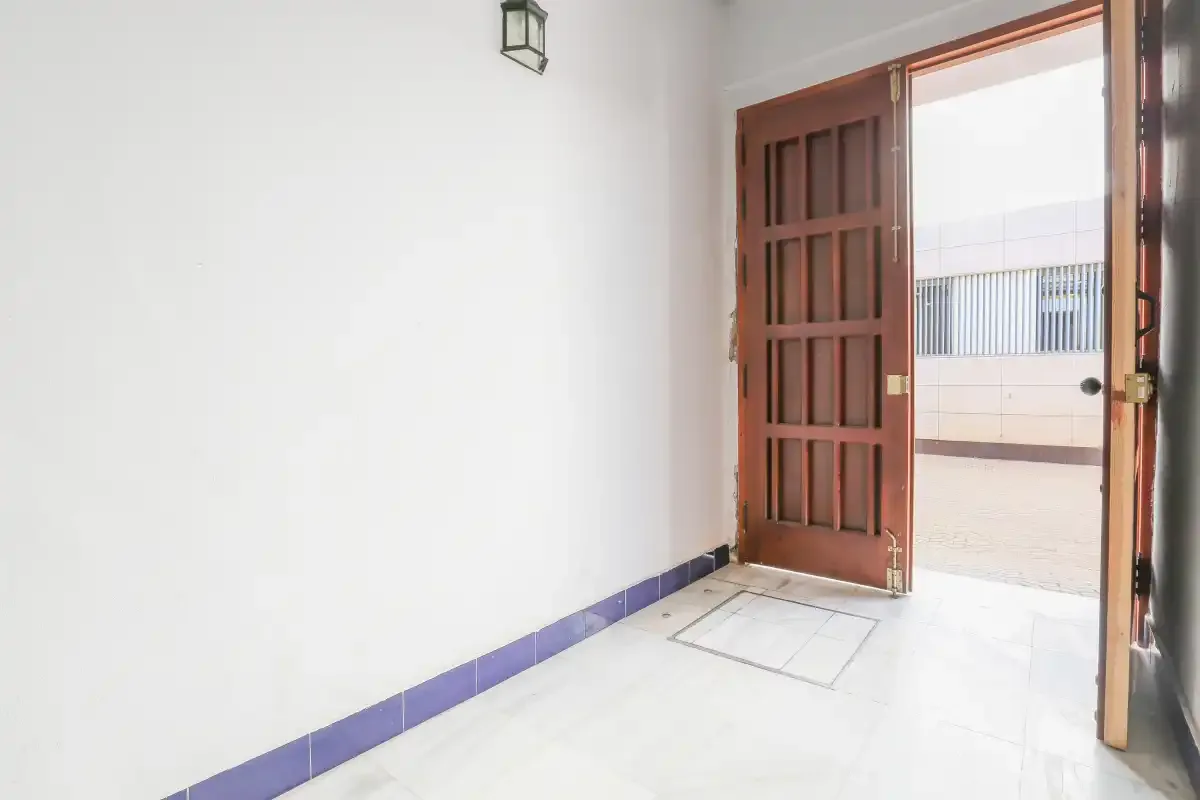 A bright entryway with an open wooden door leading to an outdoor terrace.