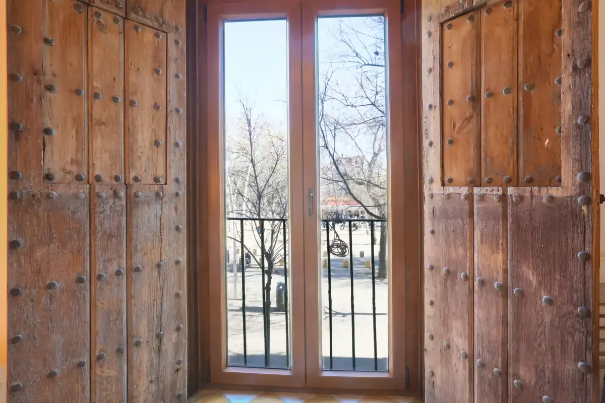 Wooden doors frame tall glass panels overlooking a tree-lined street.