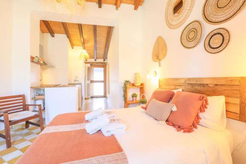 A bedroom with a bed dressed in white linens and a wooden headboard.