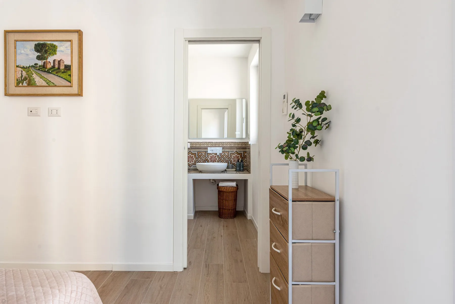 Una puerta del dormitorio da a una zona de tocador con espejo y planta en maceta.