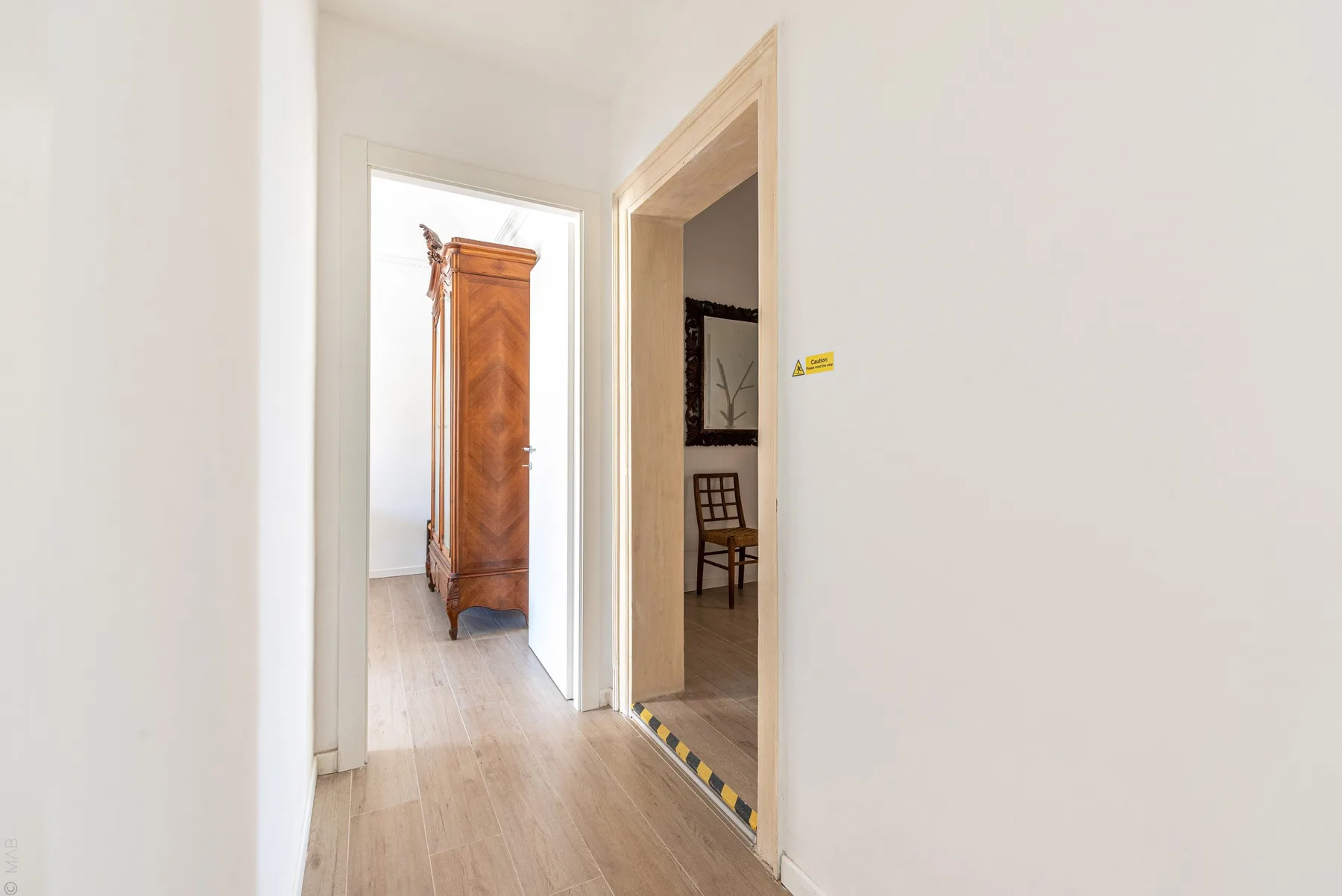 Un pasillo luminoso con suelo de madera y puertas abiertas.