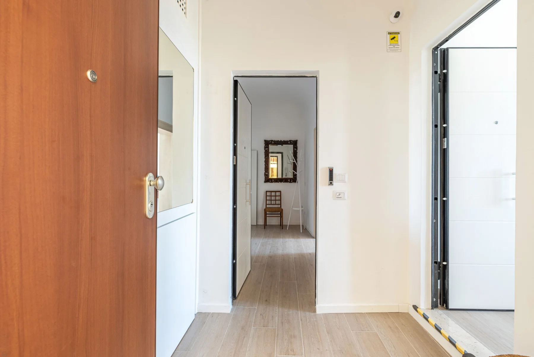 Una entrada con una puerta de madera abierta y una vista al pasillo.