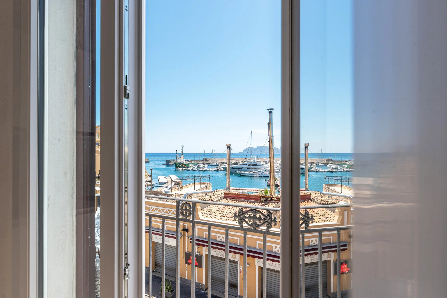 Una vista costera a través del vidrio muestra barcos, el agua y un edificio junto al mar.