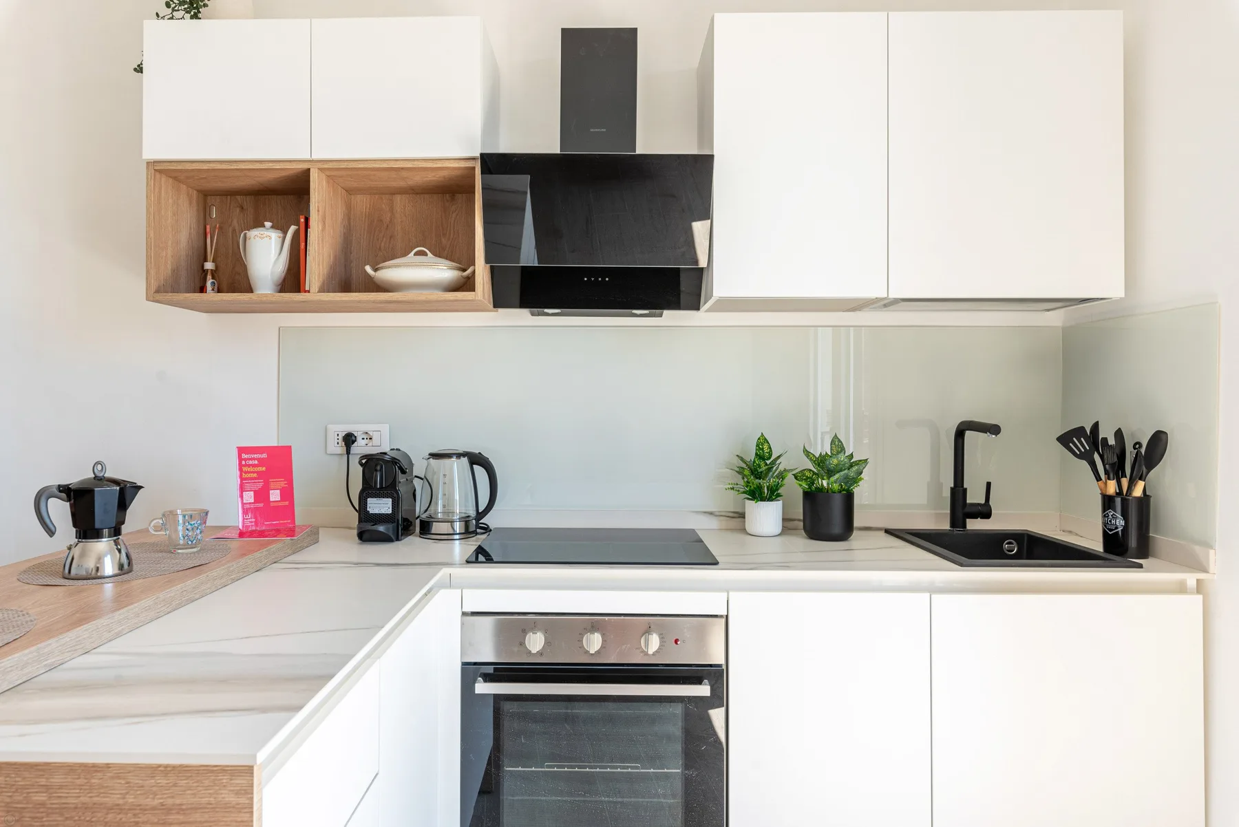 Una cocina moderna con armarios blancos, una placa de cocina y un horno.
