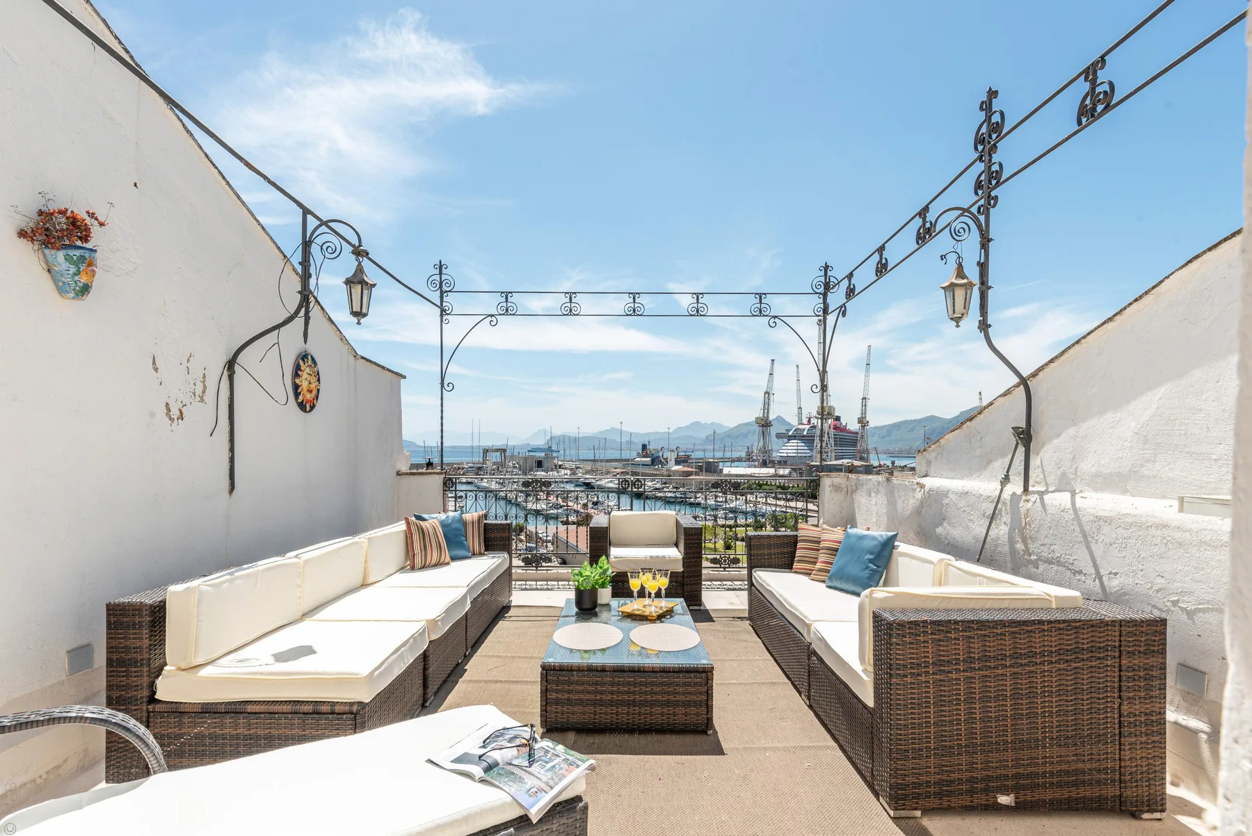 Una terraza en la azotea con asientos al aire libre y vistas al puerto y las montañas.