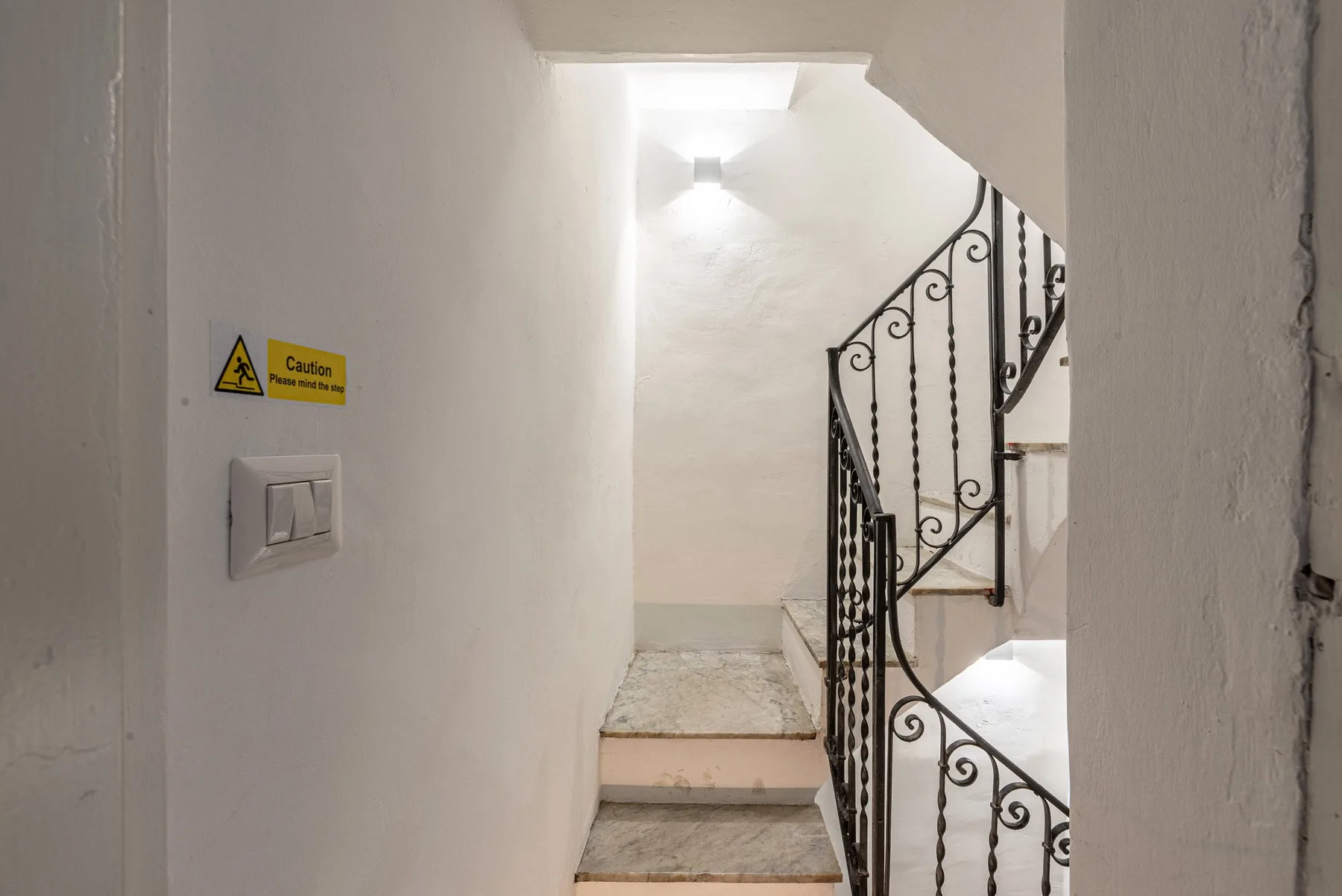 Una escalera con peldaños de piedra y una barandilla metálica decorativa.