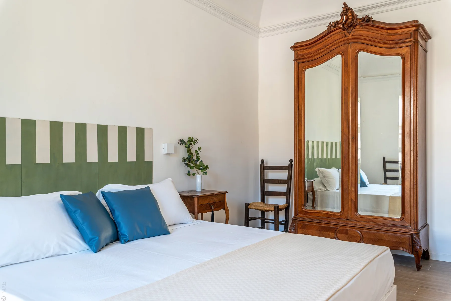 Un dormitorio con una cama, almohadas azules y un armario alto con espejos.