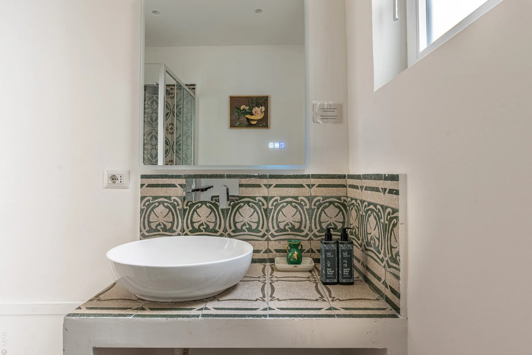 Un lavabo de baño con una pila blanca sobrepuesta y azulejos decorativos.