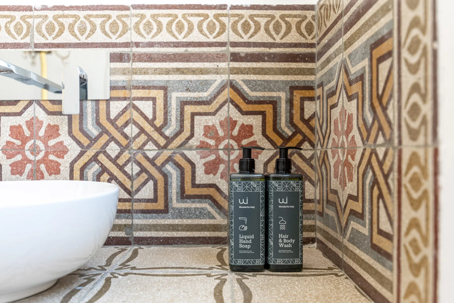 Zona de lavabo en un baño con paredes decoradas con azulejos y productos de aseo sobre la encimera.