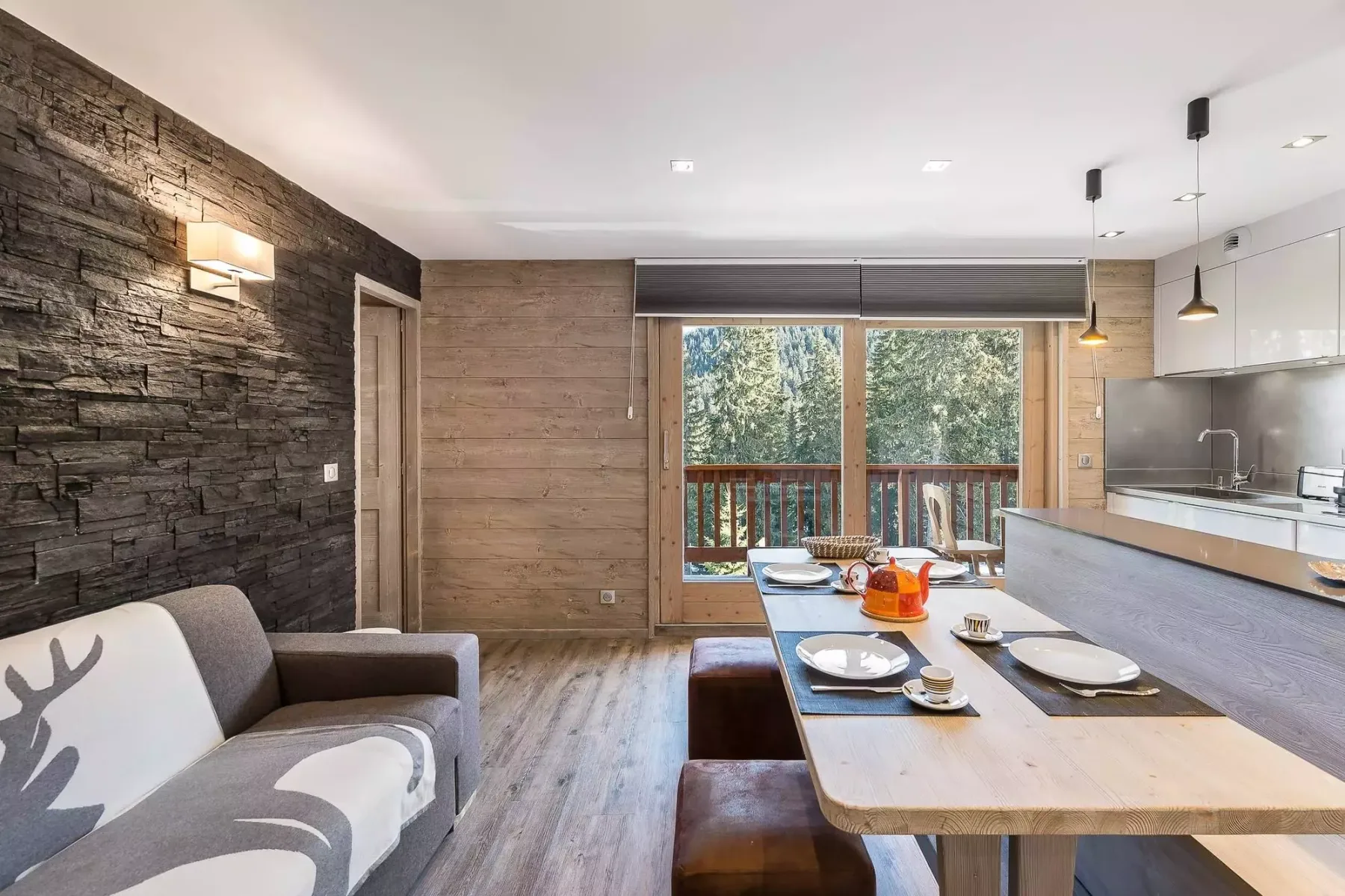 Sala-comedor de planta abierta con una cocina compacta y ventanales.