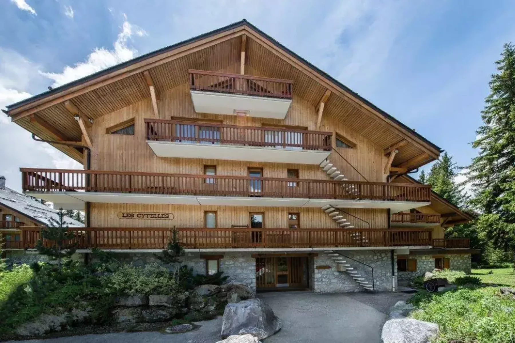 A multi-story chalet-style building with wooden balconies and a stone lower level.