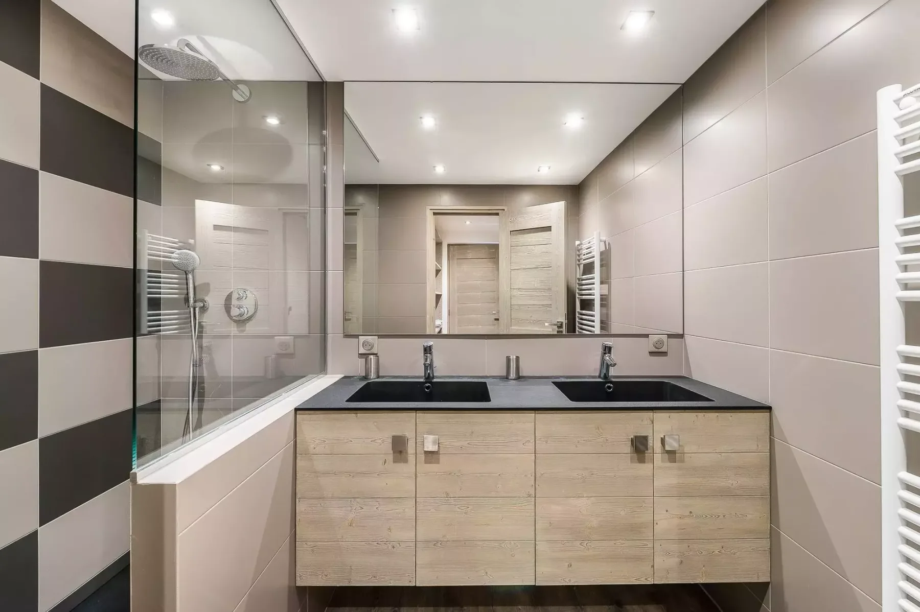 Un baño moderno con un mueble de doble lavabo y una ducha con mampara de vidrio.