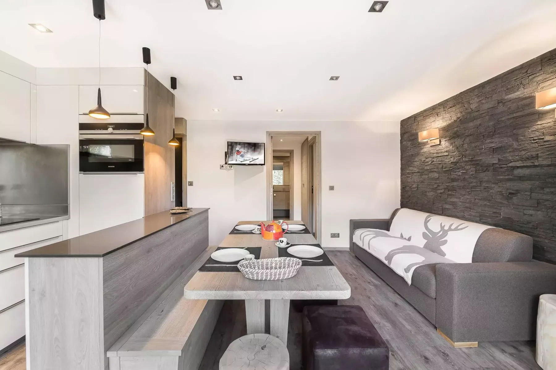 A modern living room with a dining table beside a sofa and kitchen.