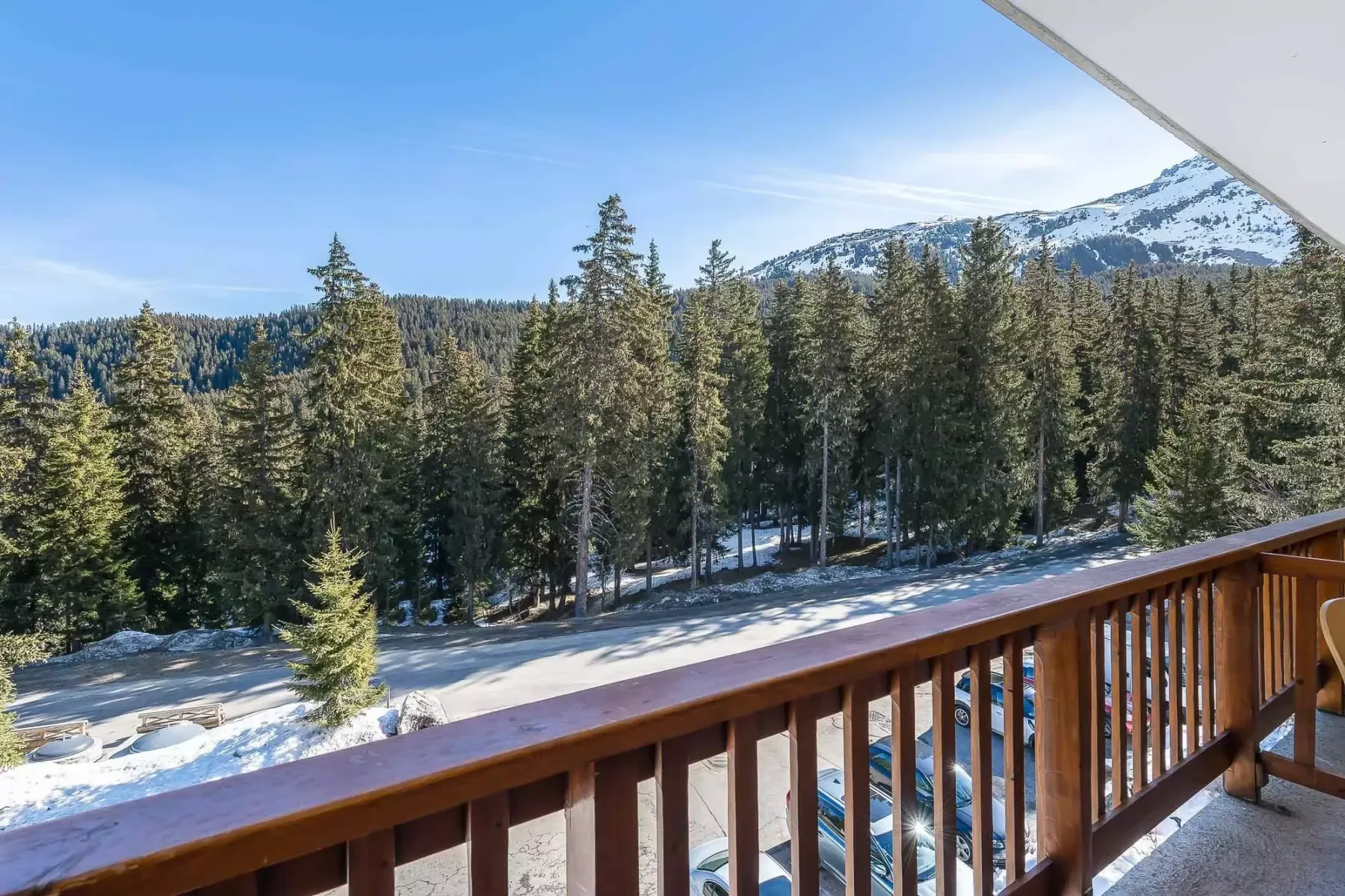 A balcony overlooks snow-dusted evergreen trees and a mountain.