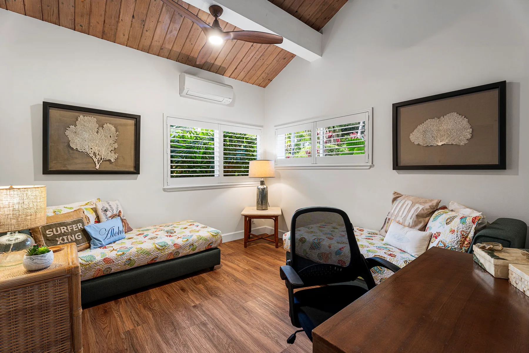 Un dormitorio luminoso con dos camas, ventanas con persianas y techo de madera.