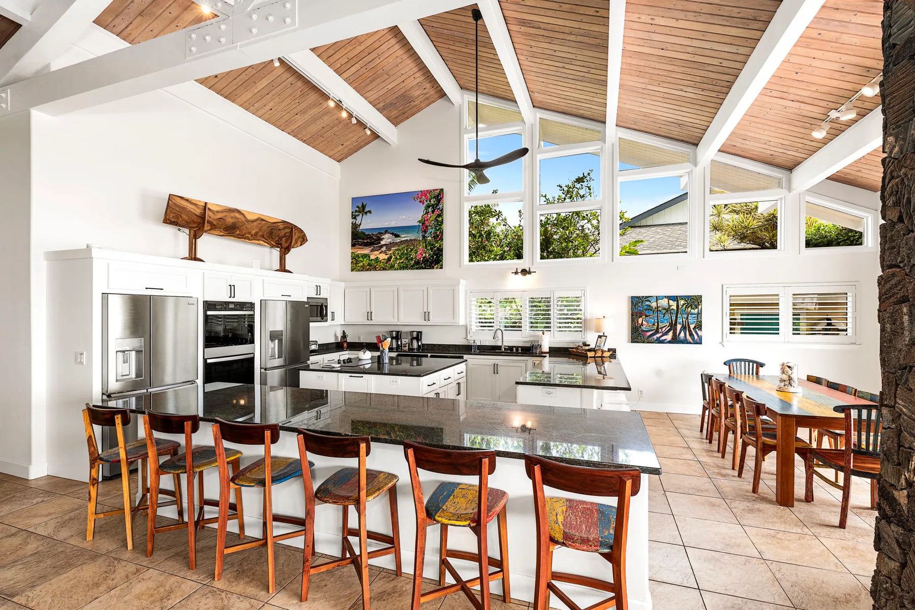 Una cocina y comedor luminosos con una isla larga y ventanas altas.