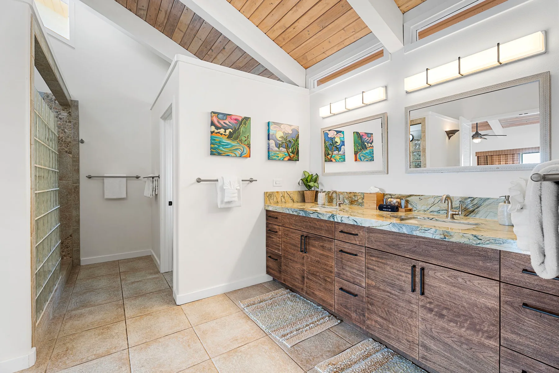 Un baño luminoso cuenta con un largo mueble de madera bajo un techo inclinado de madera.