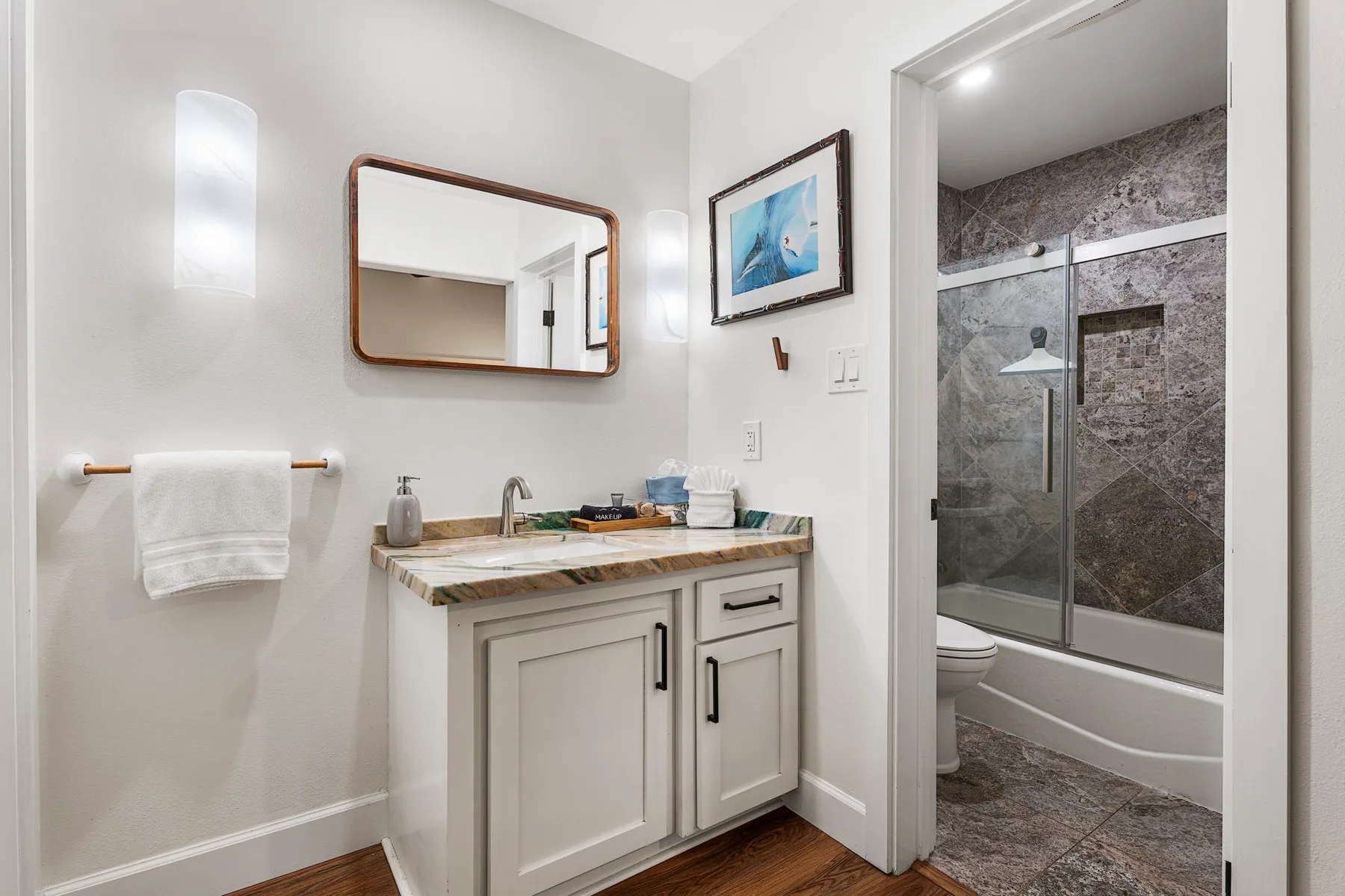 Un tocador de baño con lavabo está junto a una ducha con azulejos.