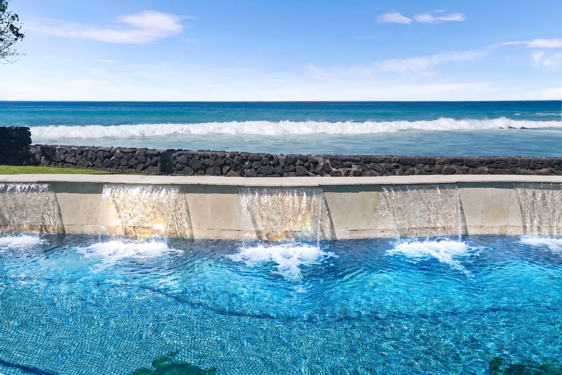 Una piscina con agua cayendo por el borde junto al océano.