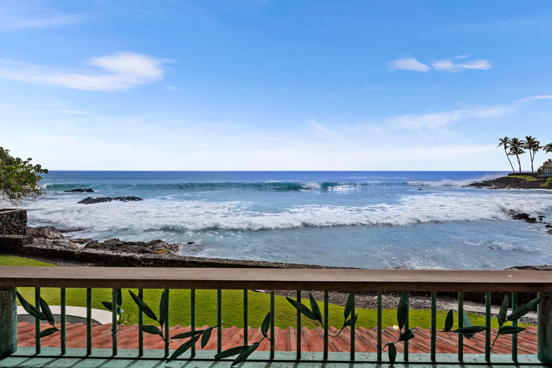 Las olas llegan a una costa rocosa, vistas detrás de la barandilla de un balcón.