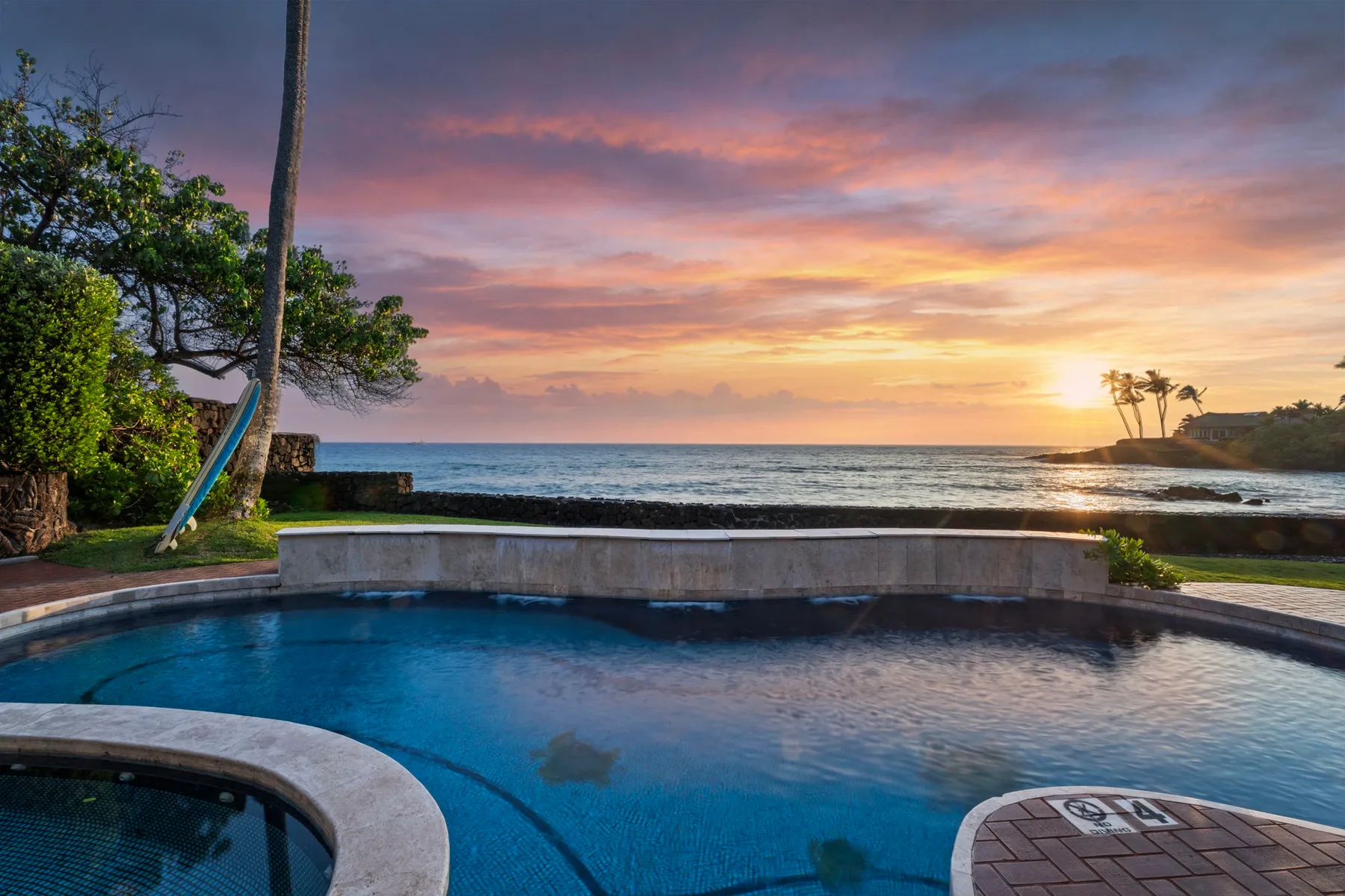 Una piscina al aire libre da al océano al atardecer.
