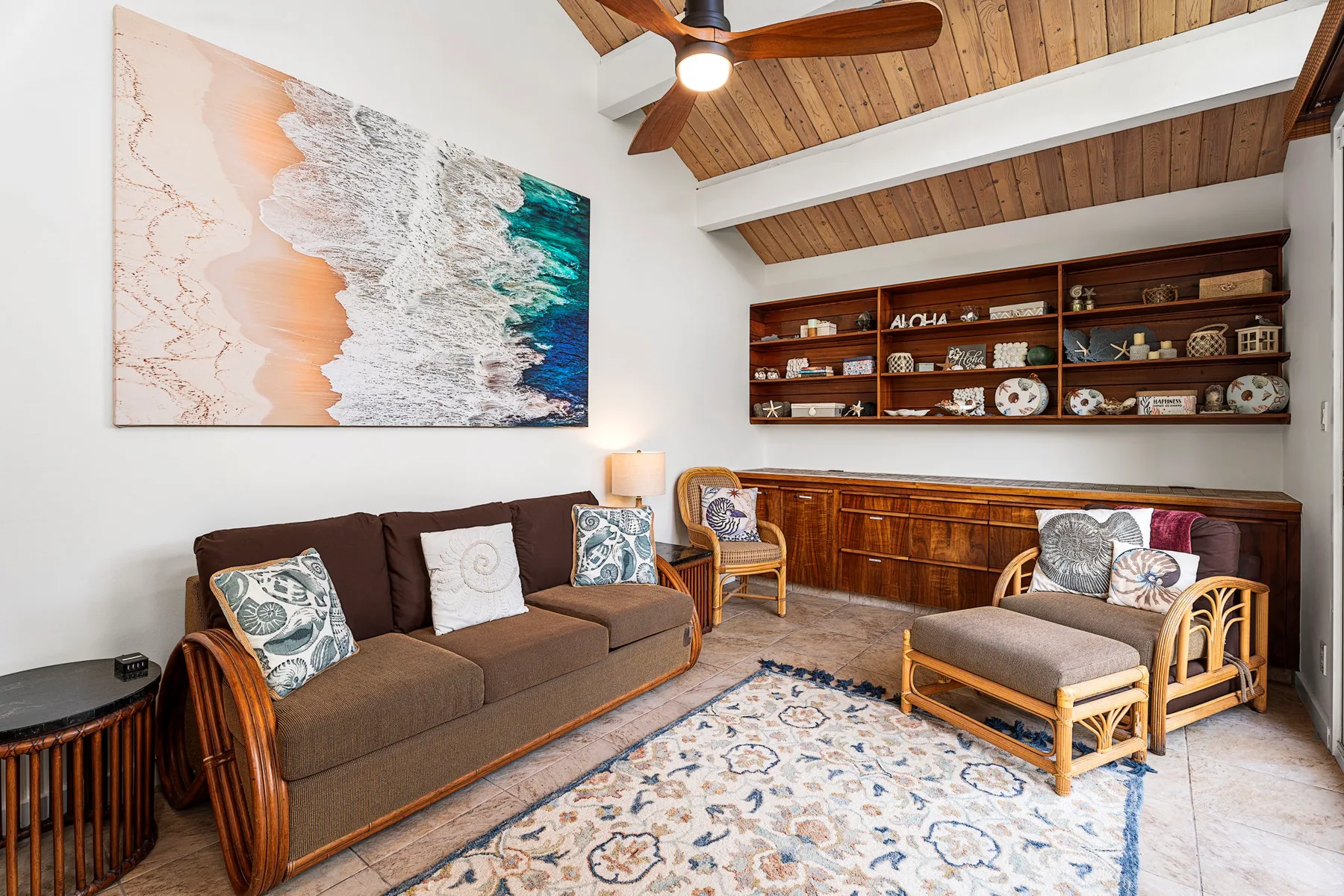 Una sala de estar con asientos, una alfombra estampada y estanterías de madera al fondo.