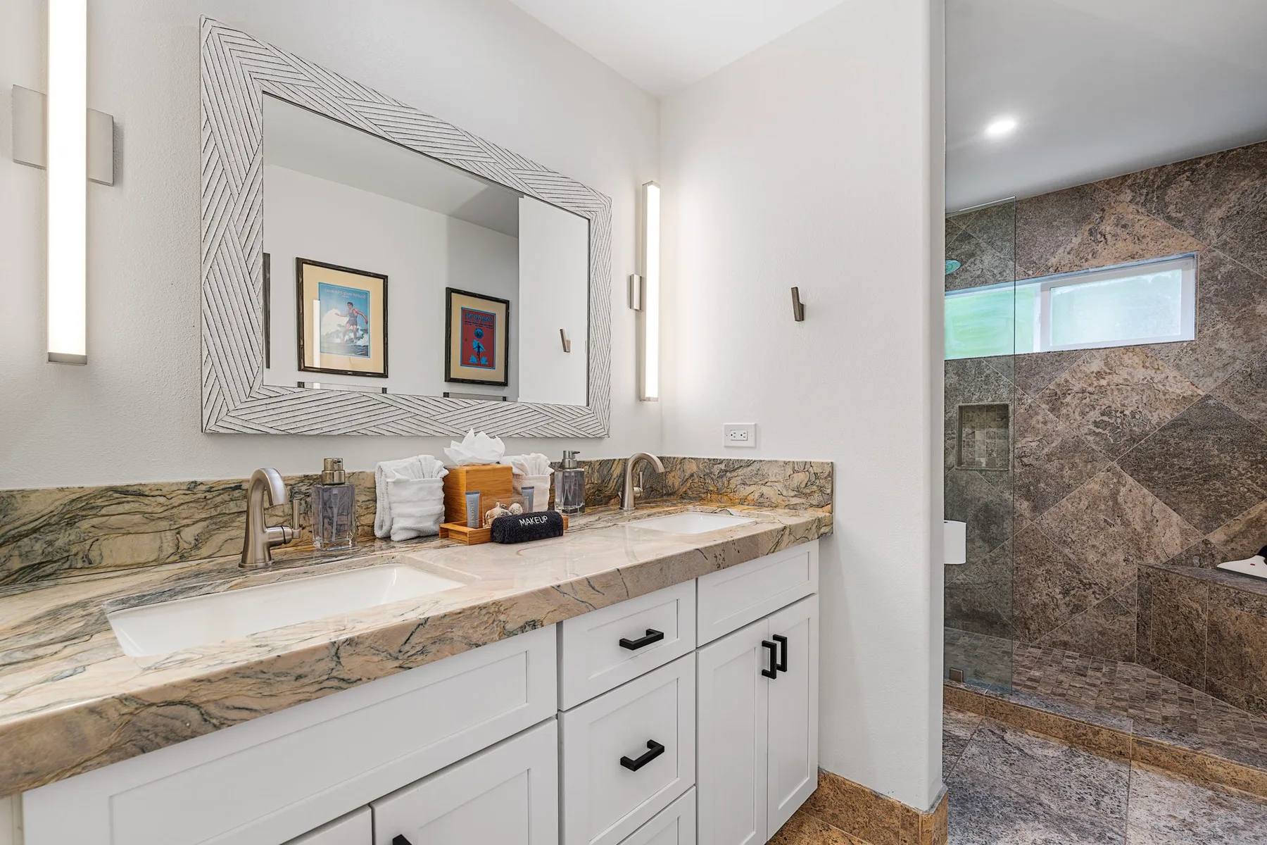 Un tocador de baño con un espejo grande junto a una ducha revestida de piedra.