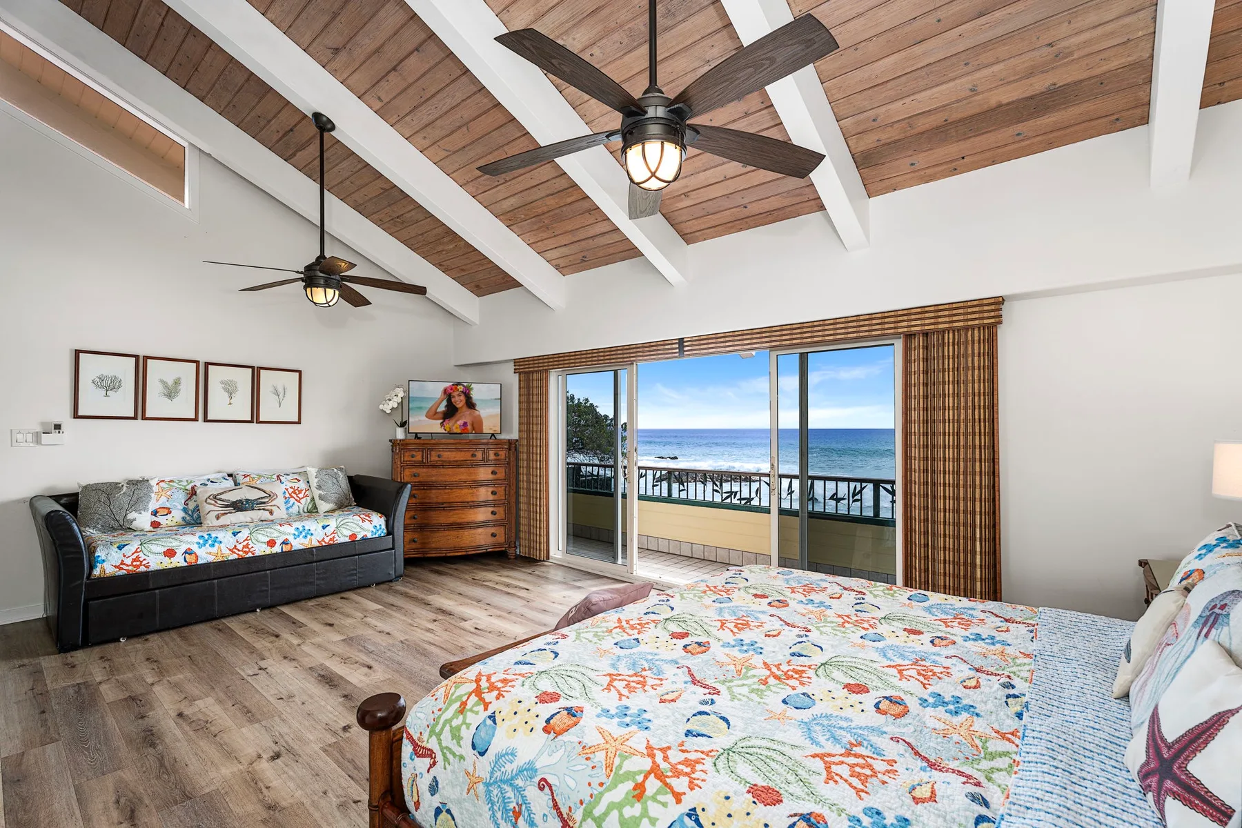 Un dormitorio con una cama, un sofá y puertas corredizas de vidrio con vista al mar.
