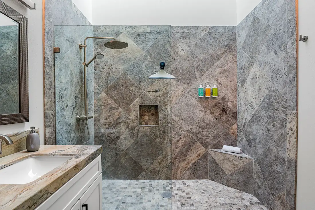 Baño con una amplia ducha revestida de azulejos y un lavabo con mueble.