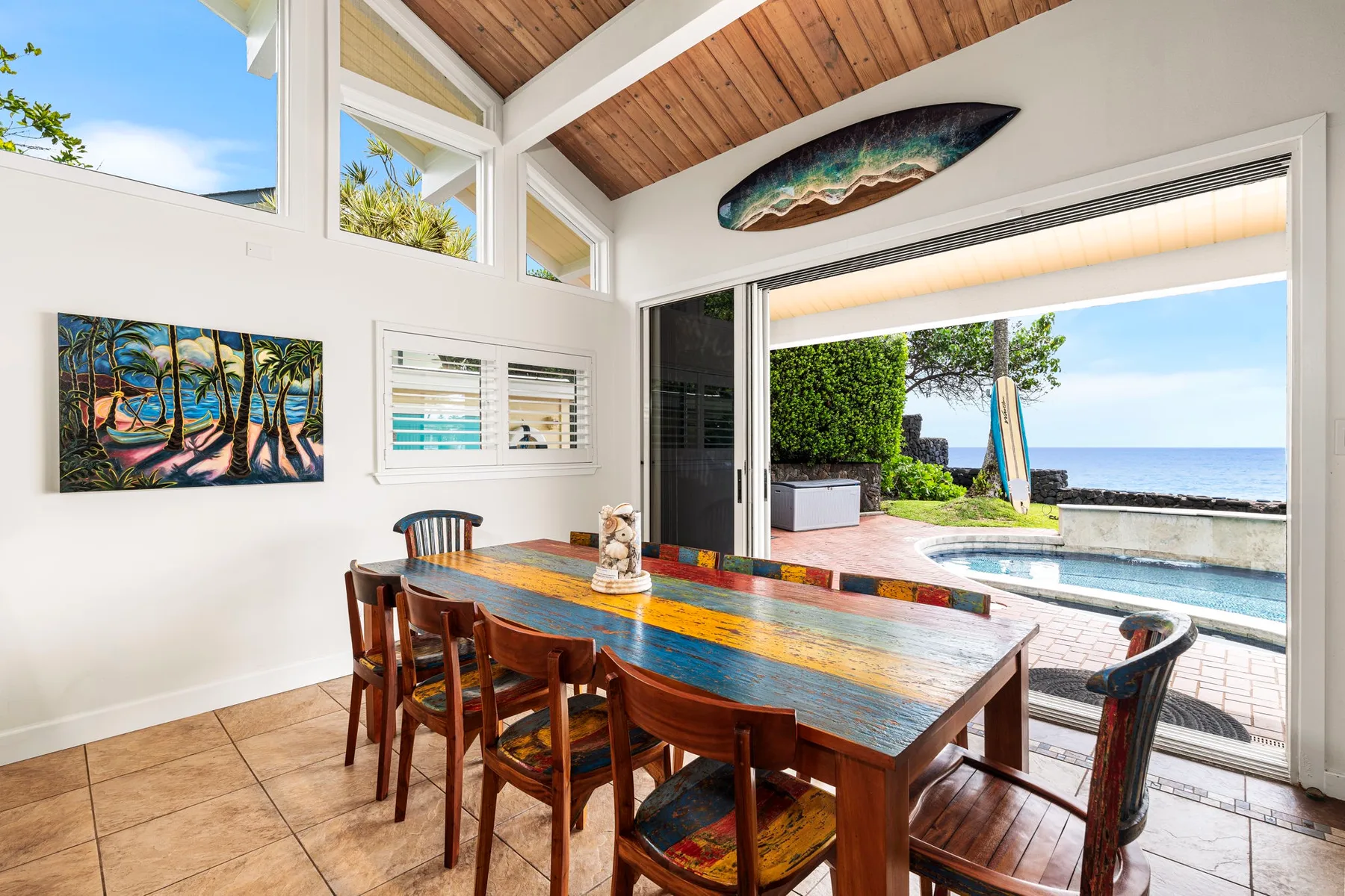Un comedor da a un patio junto a la piscina con vistas al mar.
