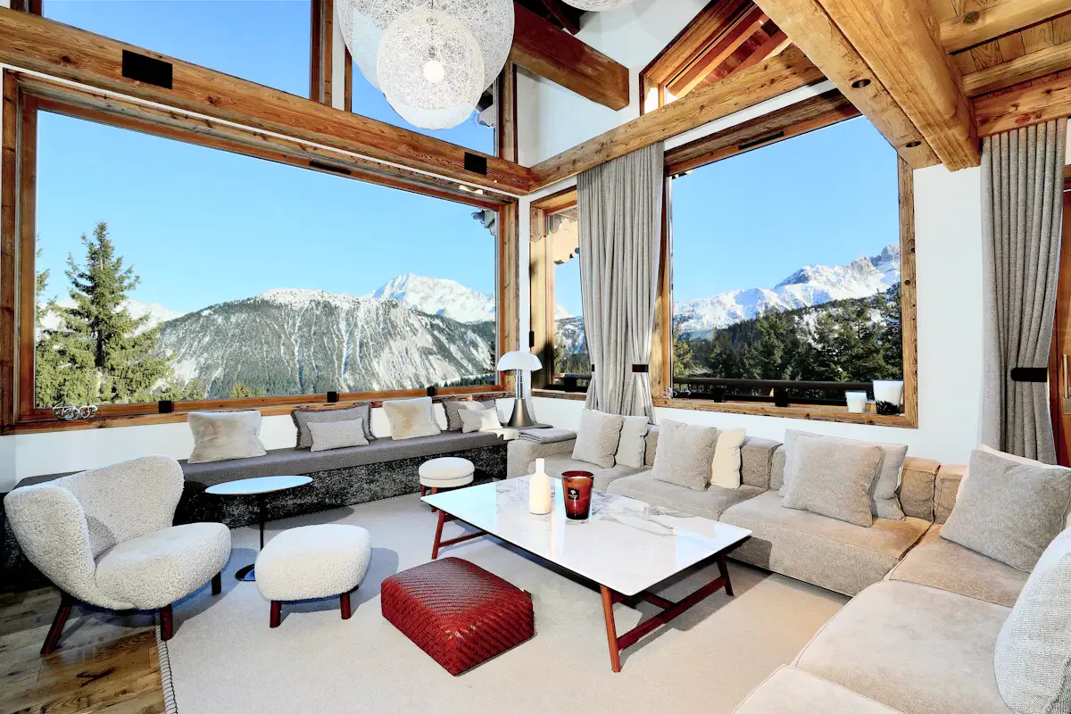 Una sala luminosa con asientos y grandes ventanas con vistas a un paisaje montañoso.
